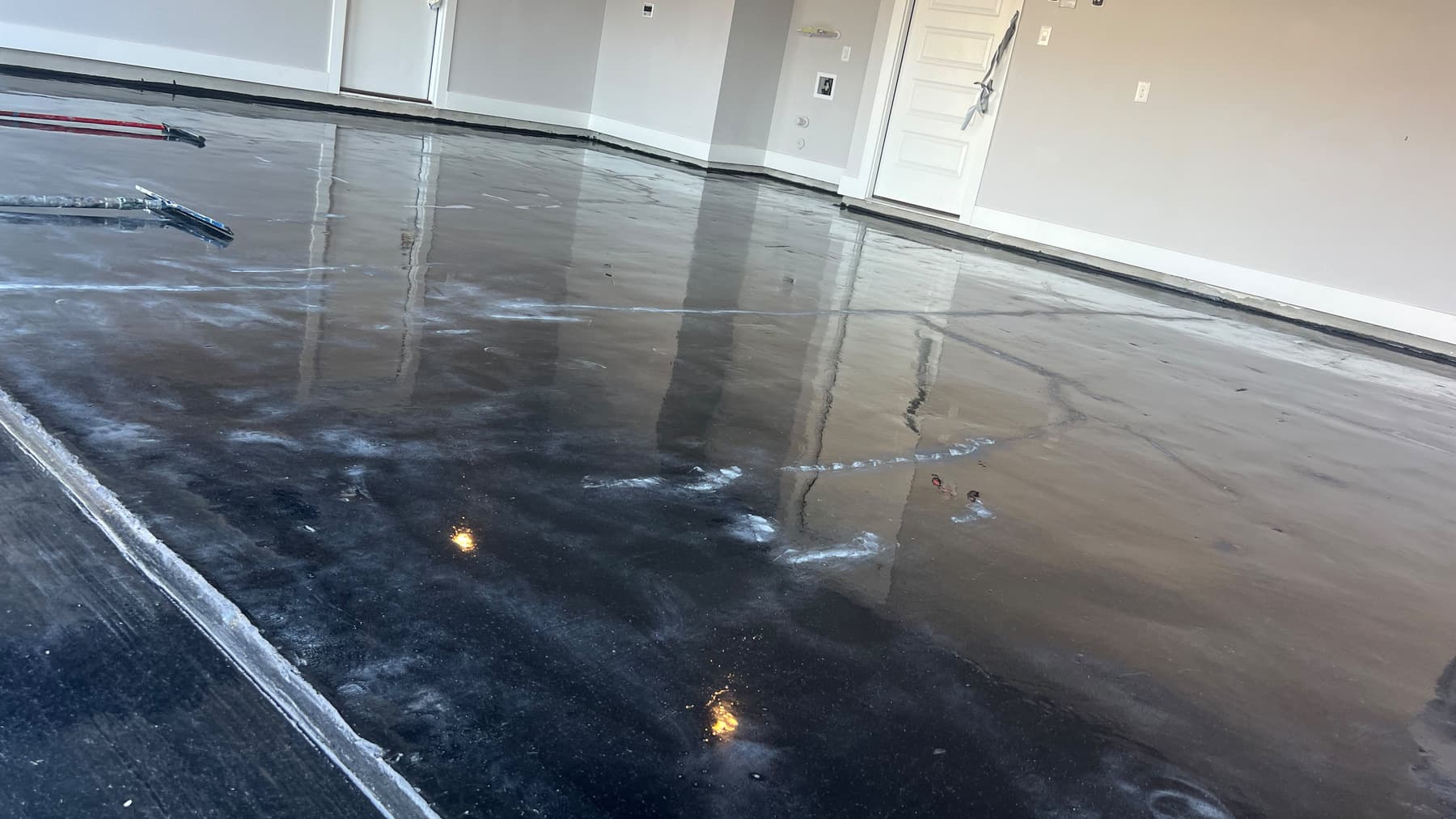 Reflective charcoal metallic epoxy being applied across a large interior floor