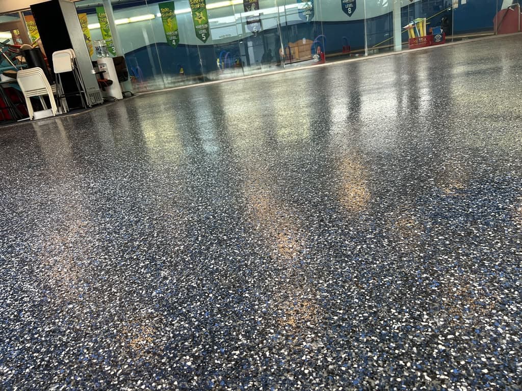 Completed dark flake epoxy floor across a public-facing commercial interior