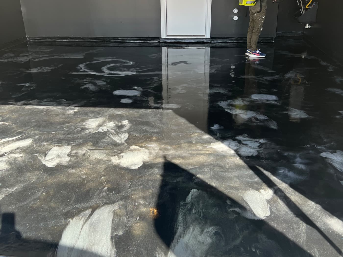 Installer completing a reflective black and silver metallic epoxy floor