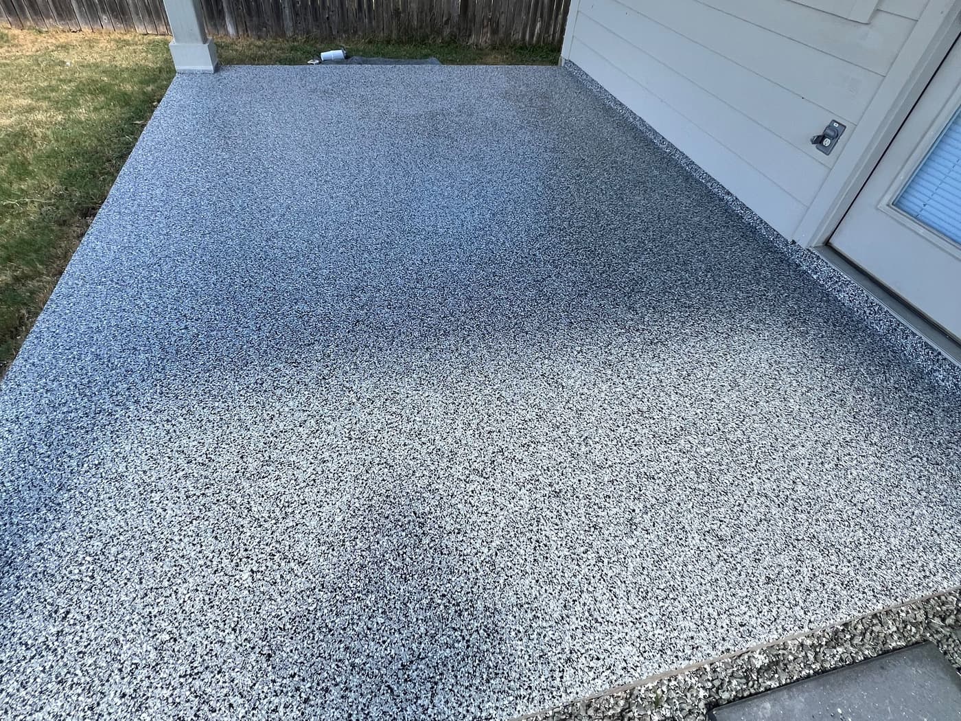 Completed gray textured coating across an exterior landing beside a back entry