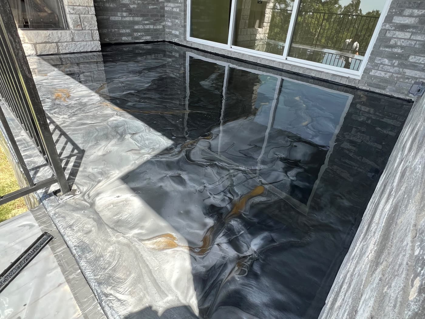 Completed black, gray, white, and gold exterior entry coating framed by stone and windows