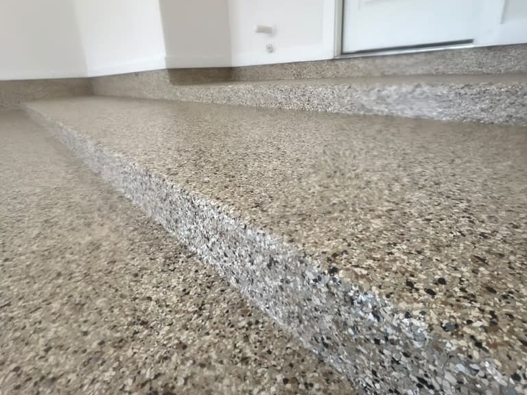 Close view of completed neutral Flake epoxy coating across a floor edge and steps