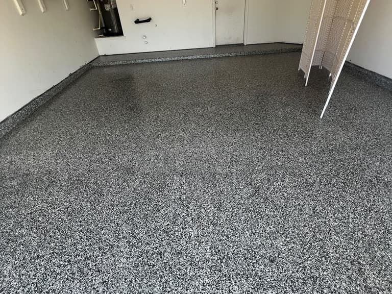 Completed dark gray flake floor extending through a garage workspace
