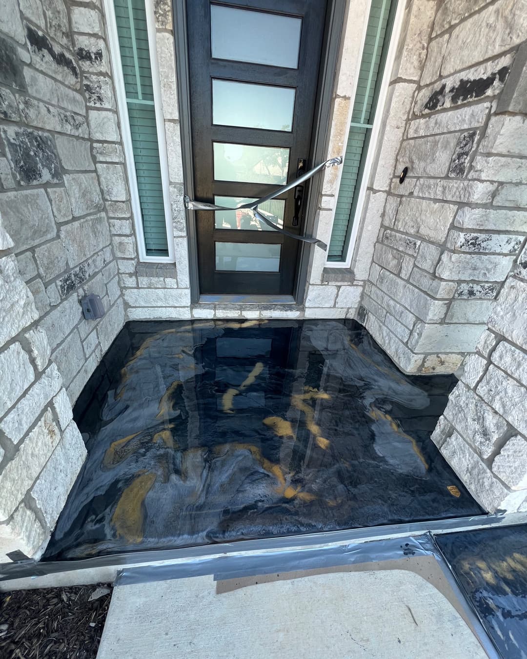 Black, gray, and gold metallic floor at a stone residential entry