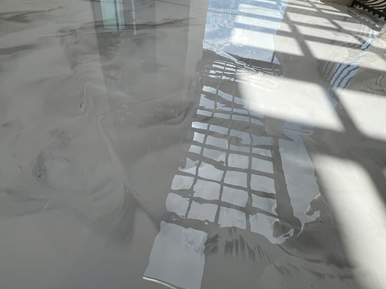 Sunlight and railing reflections across a completed exterior floor surface